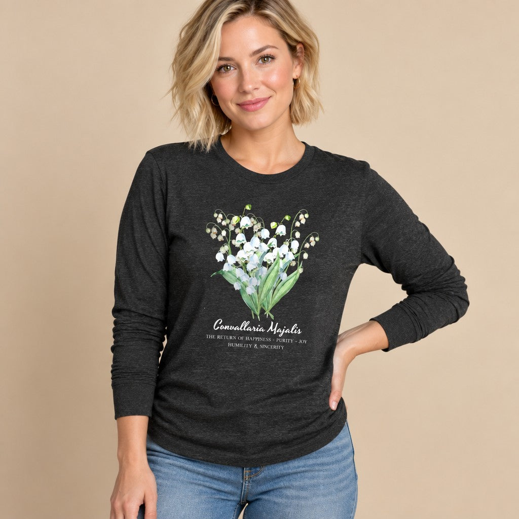 Woman wearing a dark grey heather Bella Canvas 3501 long sleeve shirt featuring a vintage cottagecore watercolor Lily of the Valley botanical bouquet, floral illustration for botanical art and cottagecore lovers, by Crossroads Dandelion