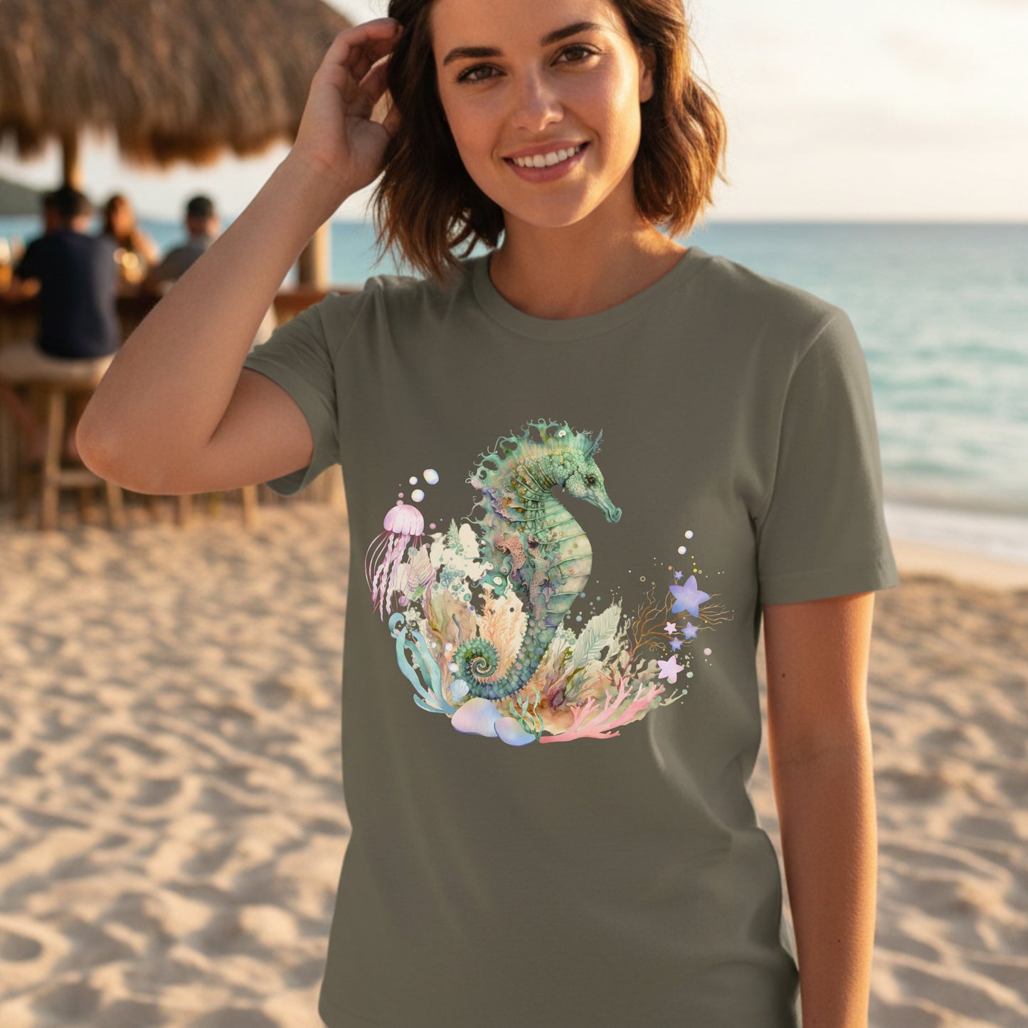 Woman wearing an army color t-shirt with a colorful seahorse design on a beach.