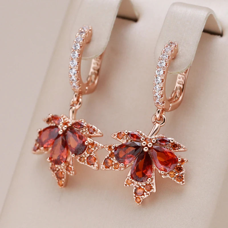 Rose gold maple earrings with red gemstones on a beige background