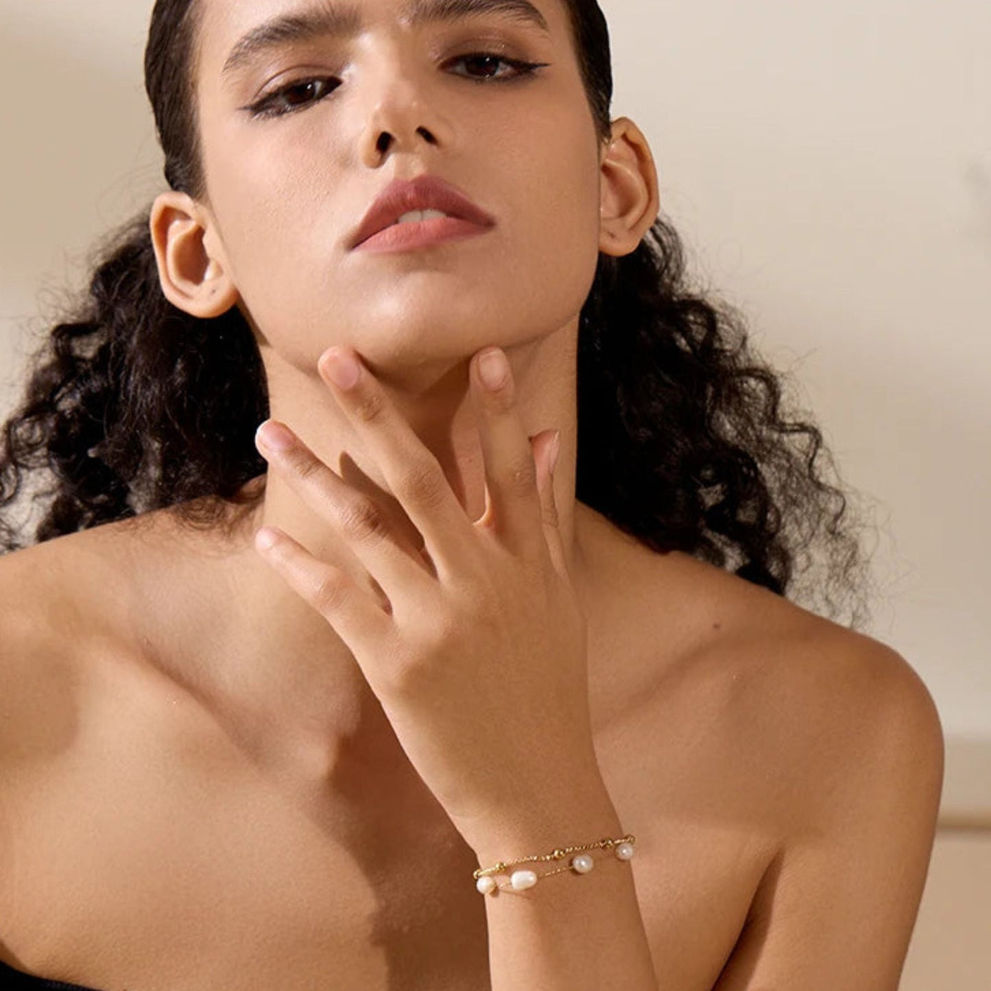 Woman wearing a pearl bracelet on a neutral background