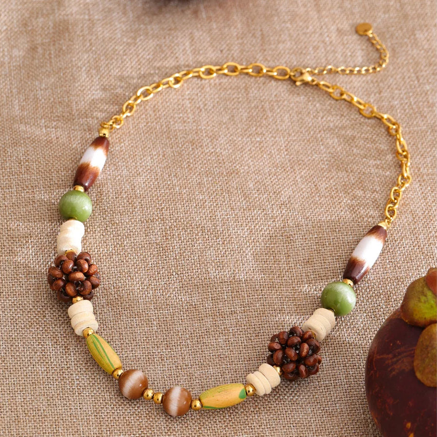 Wooded earth tones necklace with natural elements on a textured fabric background