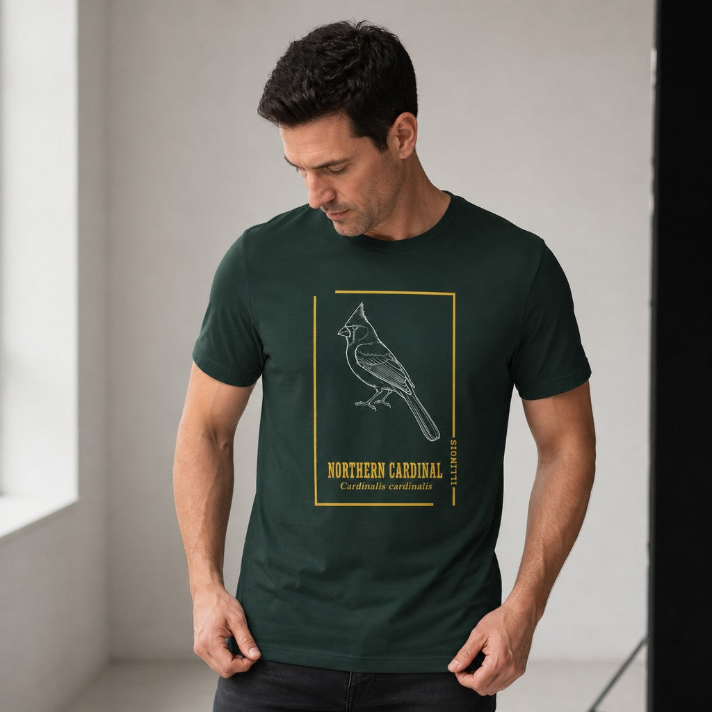 Man wearing forest green Bella Canvas 3001 t-shirt featuring a vintage white line art northern cardinal illustration with golden minimalist borders and antique botanical typography, styled for birders and nature lovers, indoor modern setting, by Crossroads Dandelion