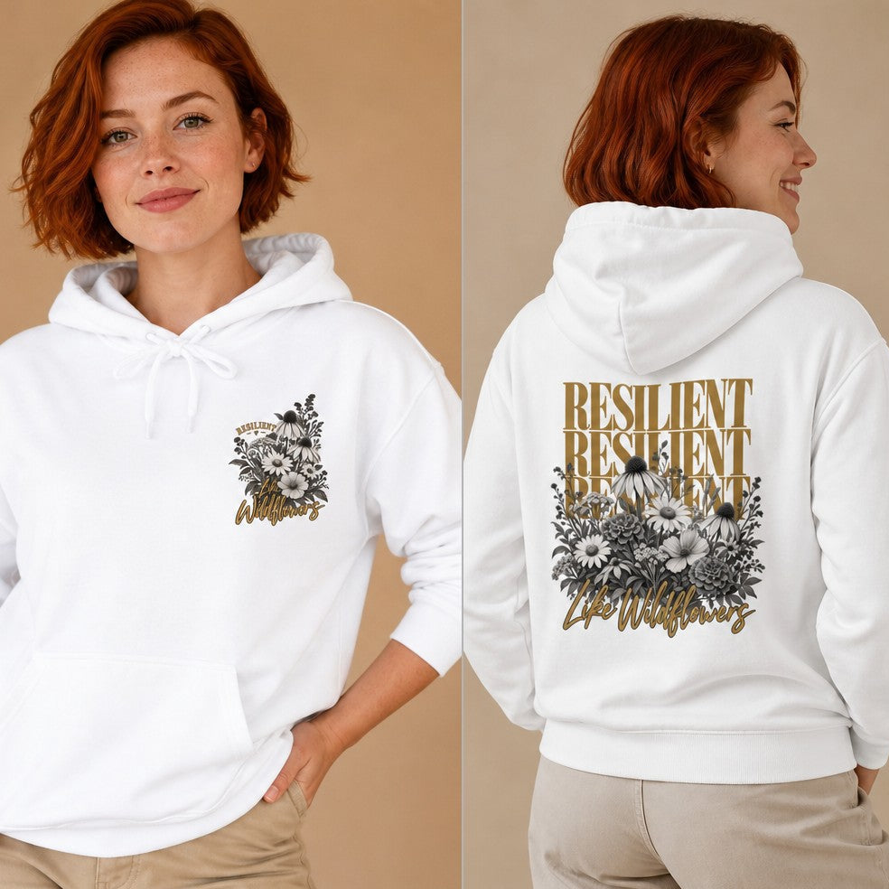 Red-haired woman wearing a white hoodie featuring a boho wildflower bouquet, gold 'Resilient' text in bold across the back, handwritten 'Life Wildflowers' overlay, casual indoor setting, designed for women, by Crossroads Dandelion