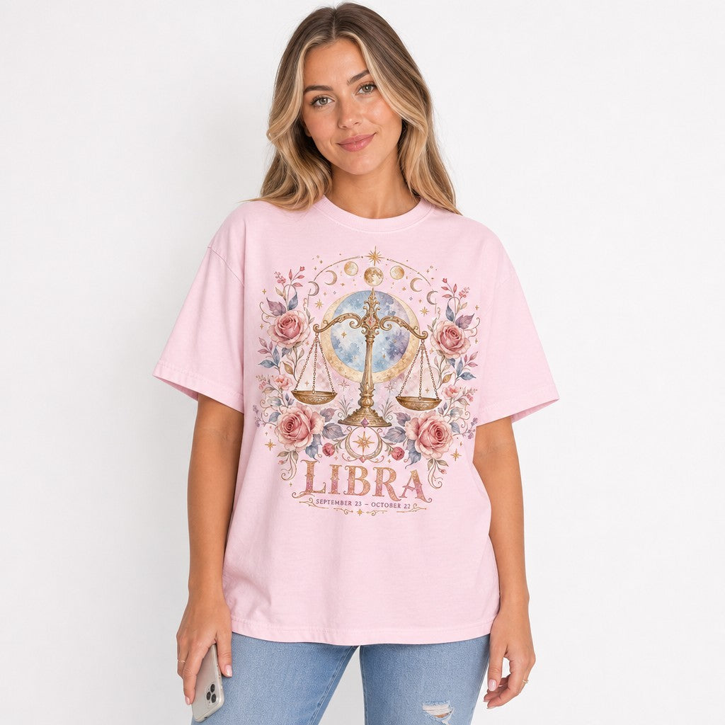 Woman wearing a blossom pink Comfort Colors 1717 t-shirt with a boho watercolor Libra scales design, surrounded by pink roses, moons, stars and cosmic accents, mystical celestial zodiac shirt for women and astrology lovers, by Crossroads Dandelion