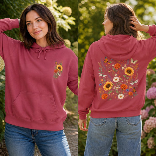 Woman wearing a crimson sweatshirt with a boho sunflower and wildflower bouquet design featuring butterflies, front and back views, standing outdoors in a garden, cozy floral apparel for women, by Crossroads Dandelion