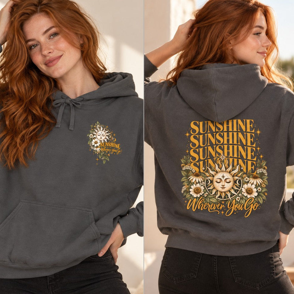 Woman wearing a pepper-colored hoodie featuring a boho retro sun and daisy floral design with the text 'sunshine wherever you go,' perfect for free-spirited women, outdoor and nature lovers, by Crossroads Dandelion