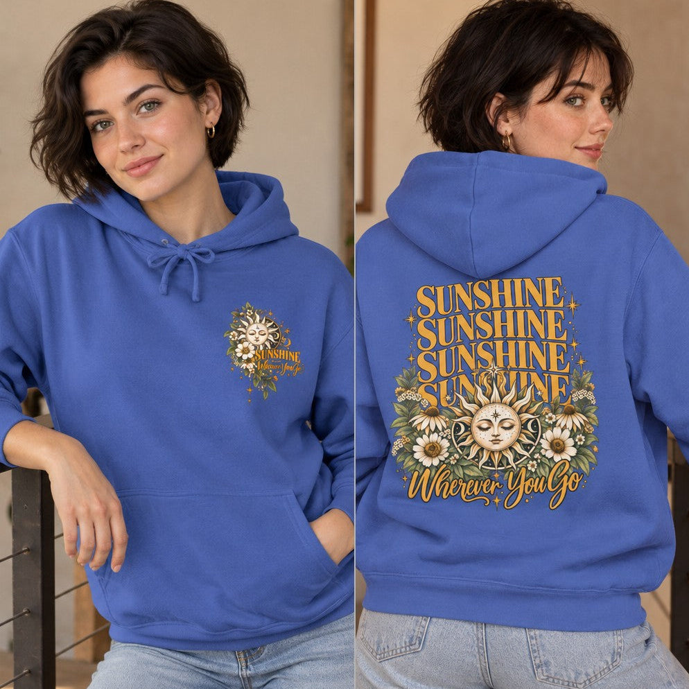 Woman in flo blue hoodie featuring a boho retro sun and florals design with text 'Sunshine Wherever You Go', relaxed indoor setting, perfect for women who love cheerful vintage-inspired apparel, by Crossroads Dandelion