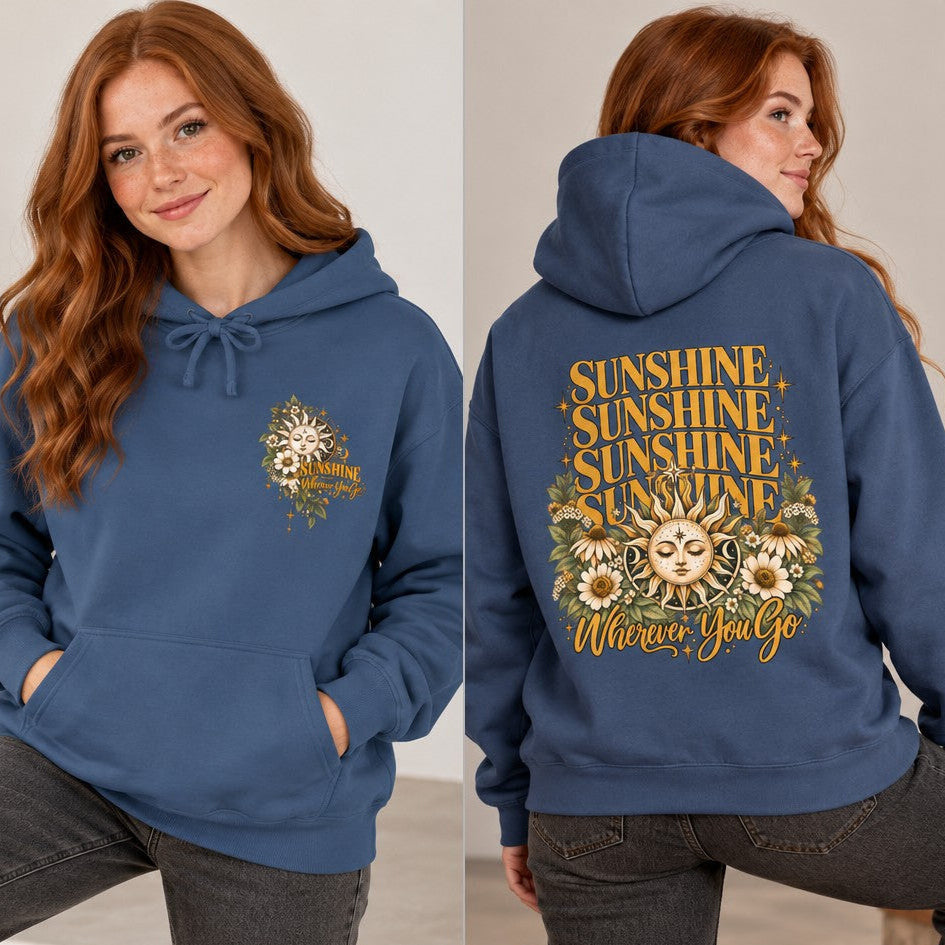 Woman wearing a true navy hoodie with a boho celestial sun, floral accents, and 'Sunshine Wherever You Go' positive message, modeled indoors, casual wear for women seeking uplifting apparel, by Crossroads Dandelion