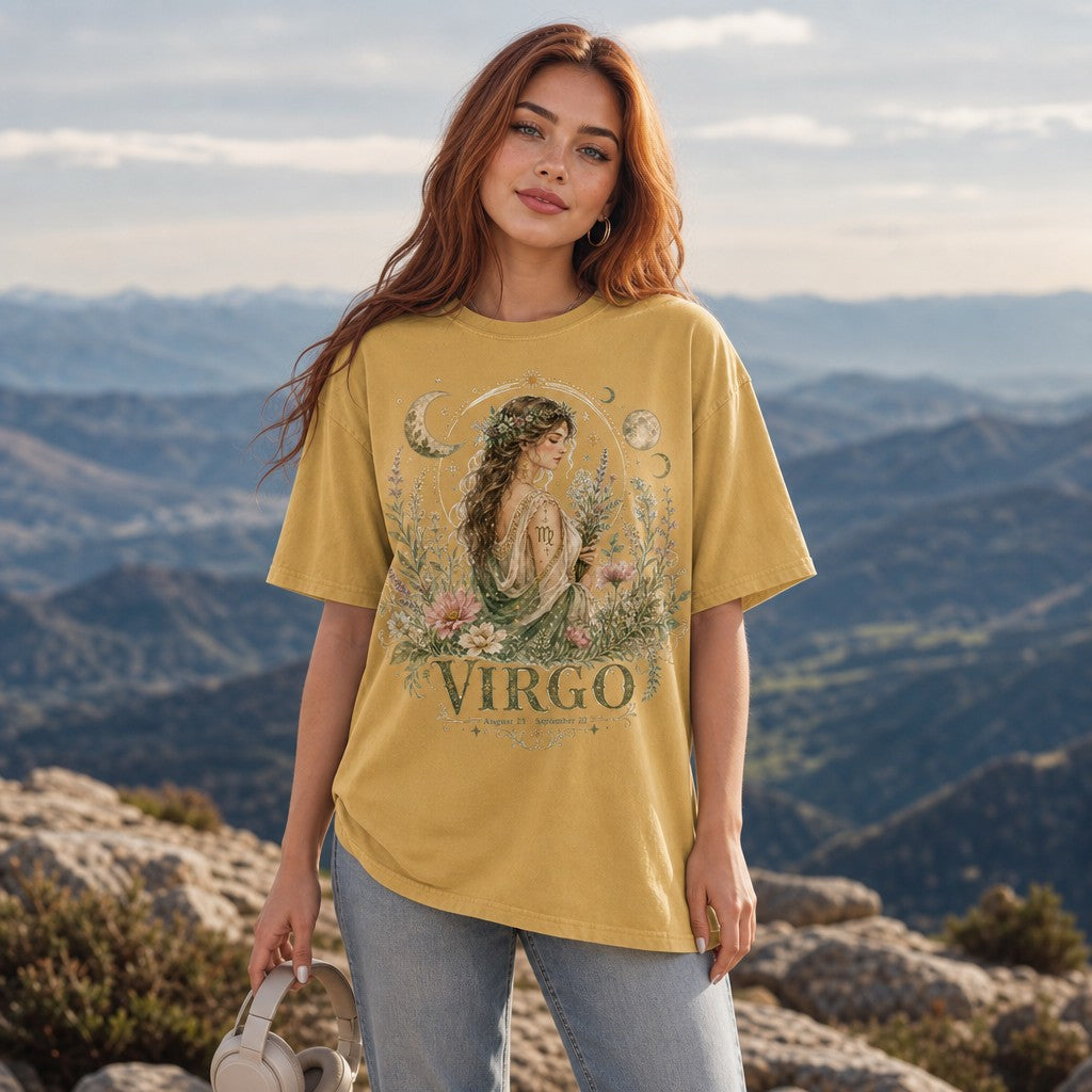 Woman in mustard Comfort Colors 1717 t-shirt featuring a whimsical boho Virgo goddess design with celestial moons, stars, and wildflowers, outdoors on a scenic mountain overlook, perfect for astrology lovers and spiritual women, by Crossroads Dandelion