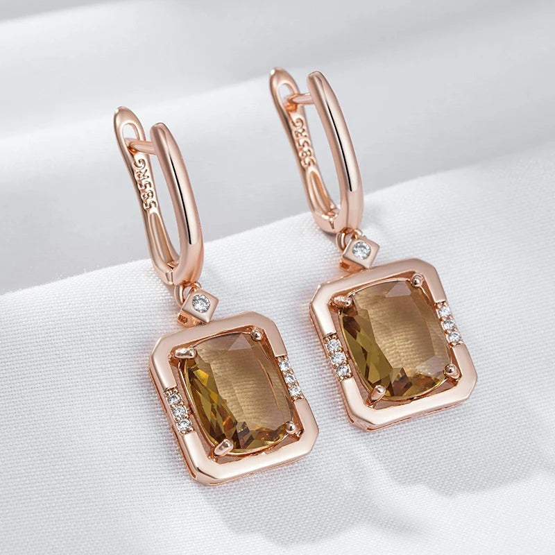 Champagne square drop earrings with clear stone accents laid on white linen