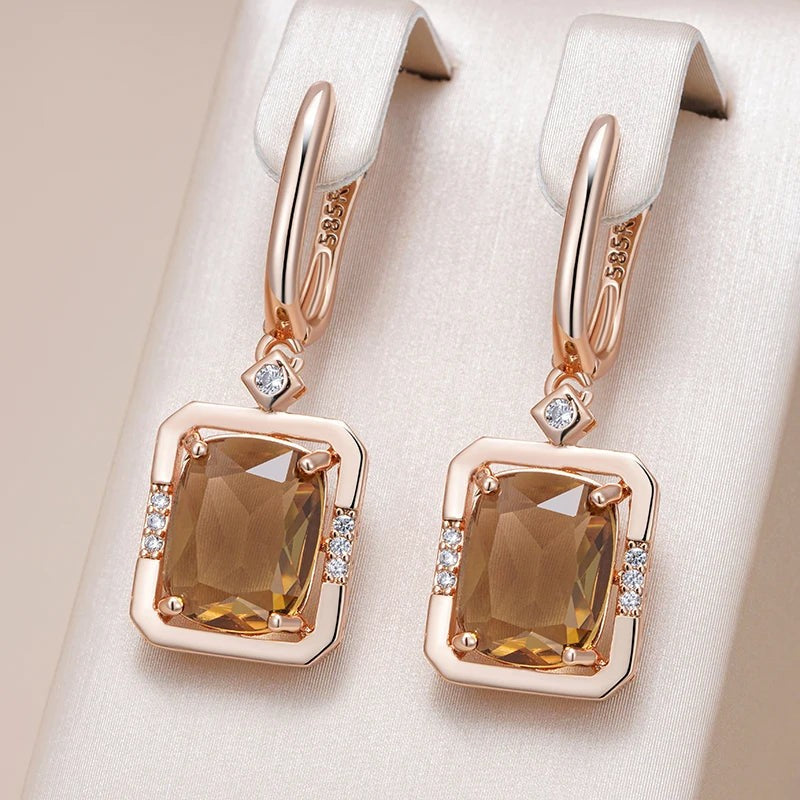 Champagne square drop earrings hanging from a cream satin jewelry display