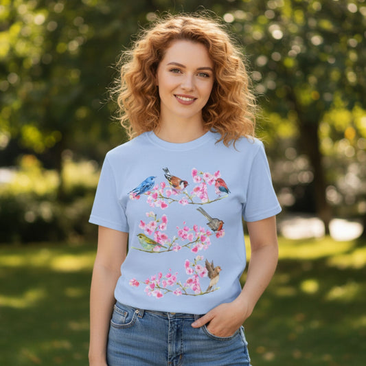 Woman wearing a Cherry Blossom Bird Shirt in Baby Blue, Bella Canvas 3001 vintage watercolor songbird botanical tee, in spring garden setting, by Crossroads Dandelion