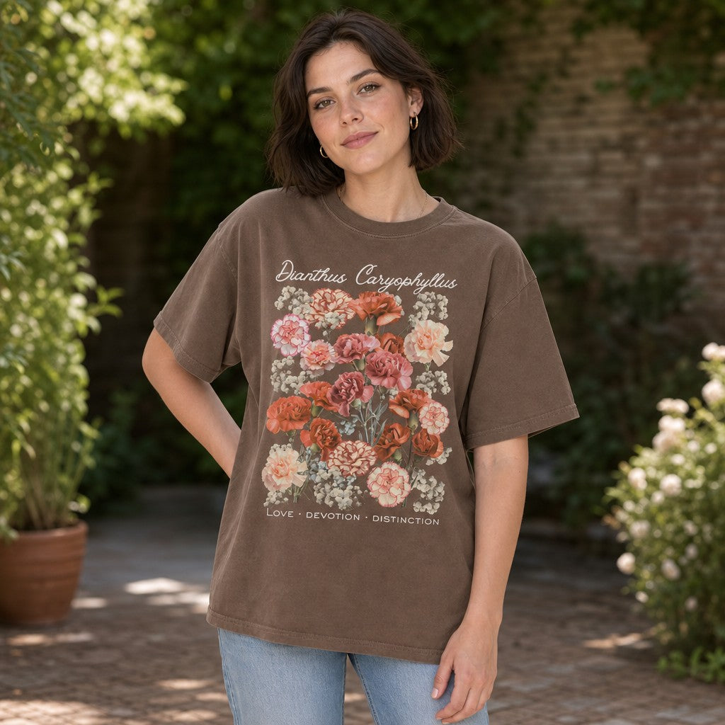 Woman wearing espresso Comfort Colors 1717 t-shirt featuring a vintage botanical illustration of peach, blush, coral, and cream carnations with baby's breath, elegant script, cottage garden setting, floral lovers, gentle souls, by Crossroads Dandelion