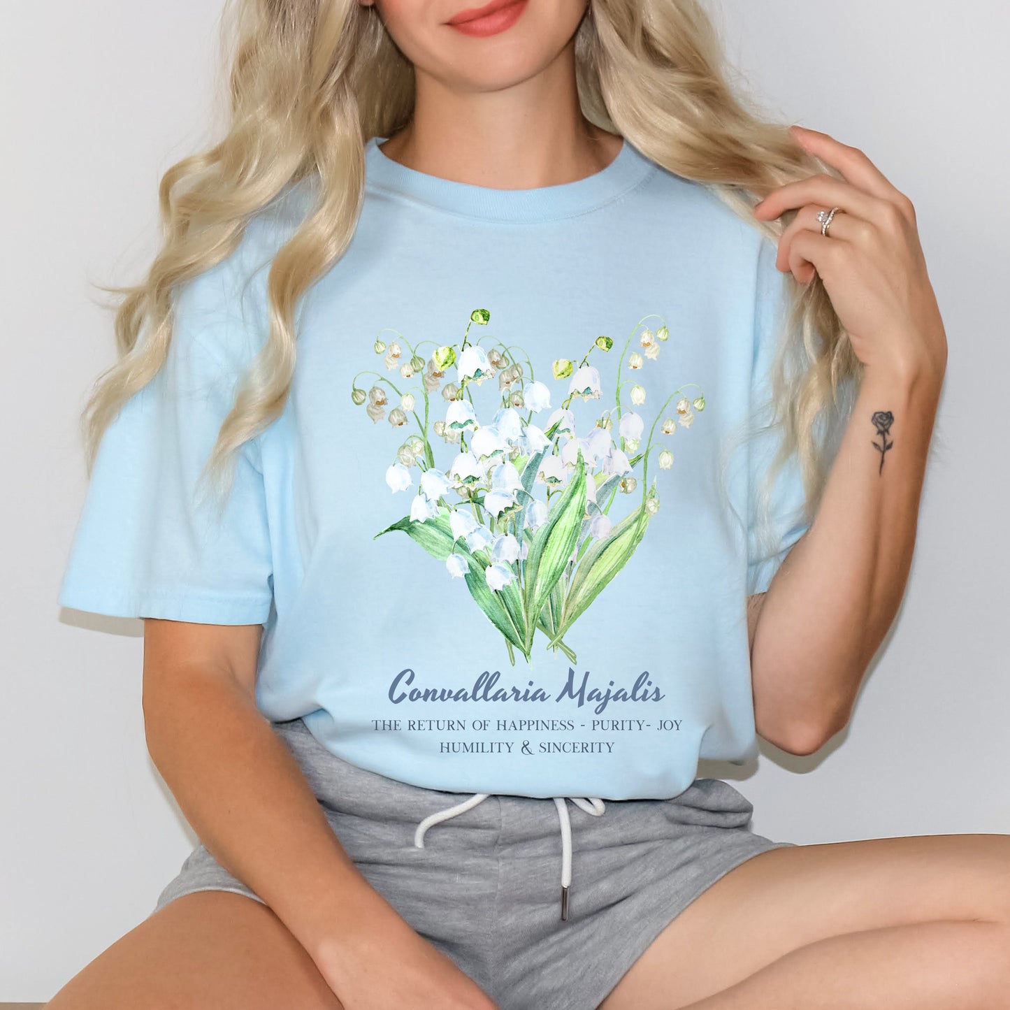 Woman wearing a Chambray watercolor Convallaria Majalis May birth month shirt – Crossroads Dandelion