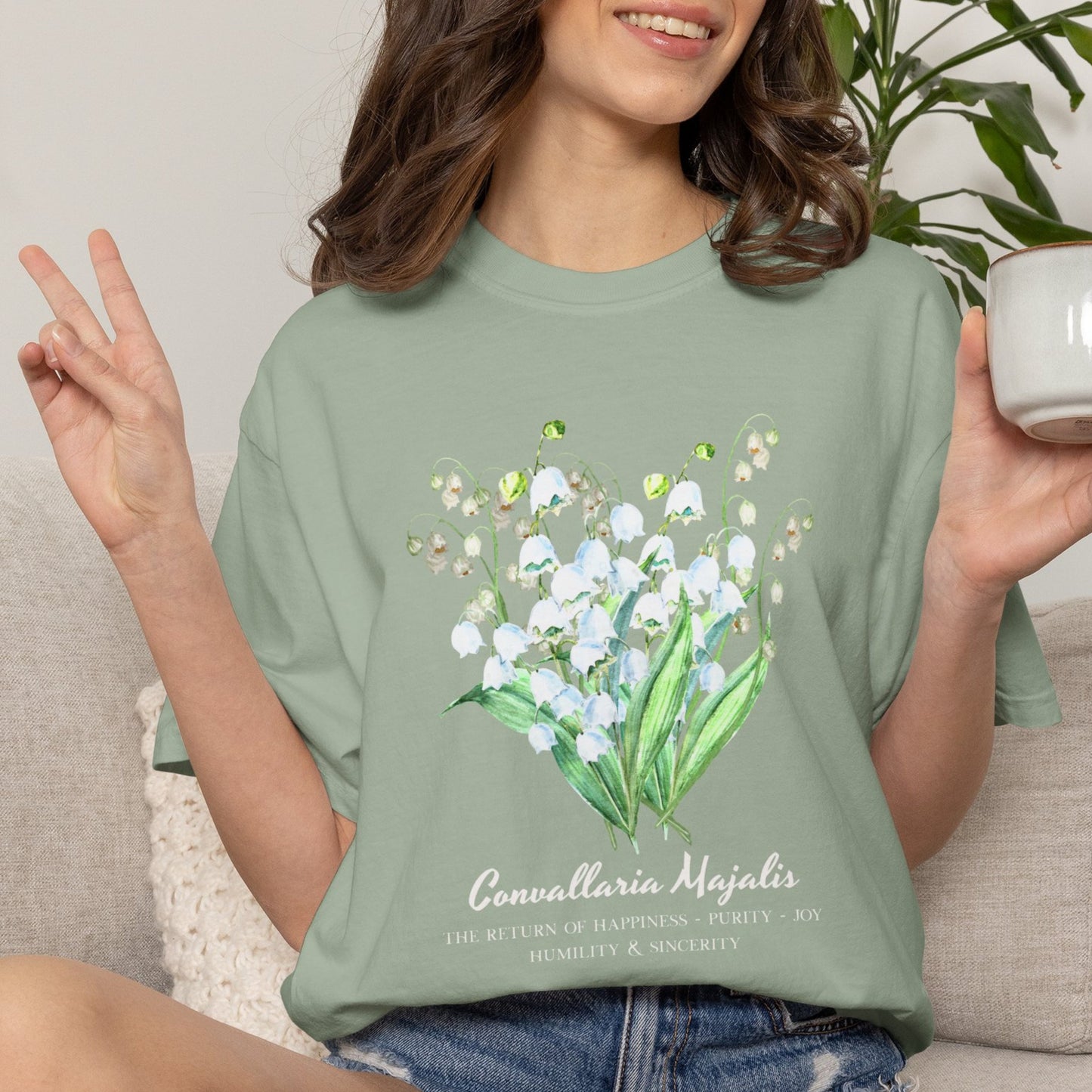 Woman smiling and wearing a Bay Comfort Colors 1717 Convallaria Majalis birth flower shirt – Crossroads Dandelion