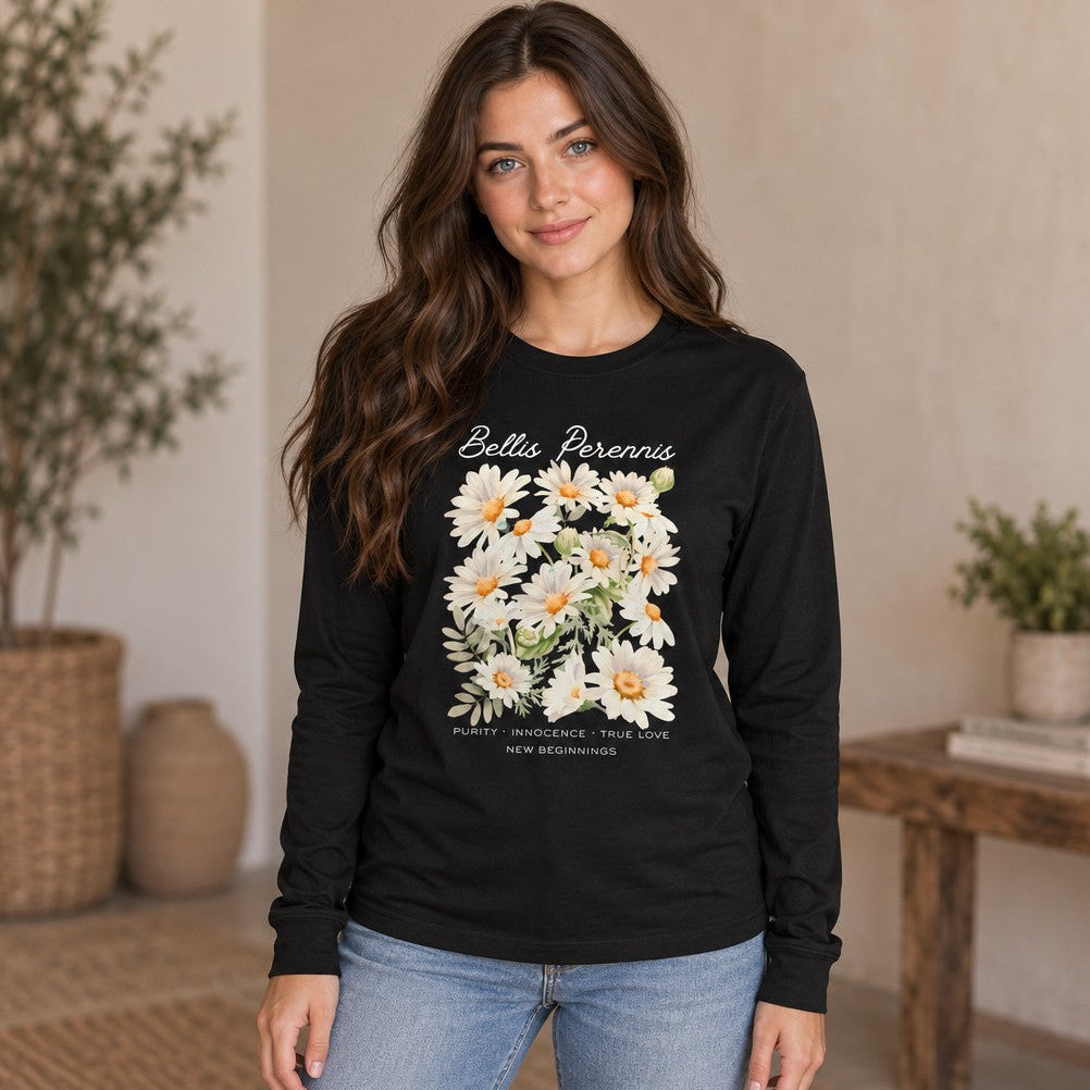 Woman wearing a black long sleeve featuring a soft watercolor Bellis perennis daisy bouquet with cursive and all-caps botanical text, cottagecore style, gentle floral symbolic design, perfect for flower lovers and new beginnings, indoor cozy scene, by Crossroads Dandelion