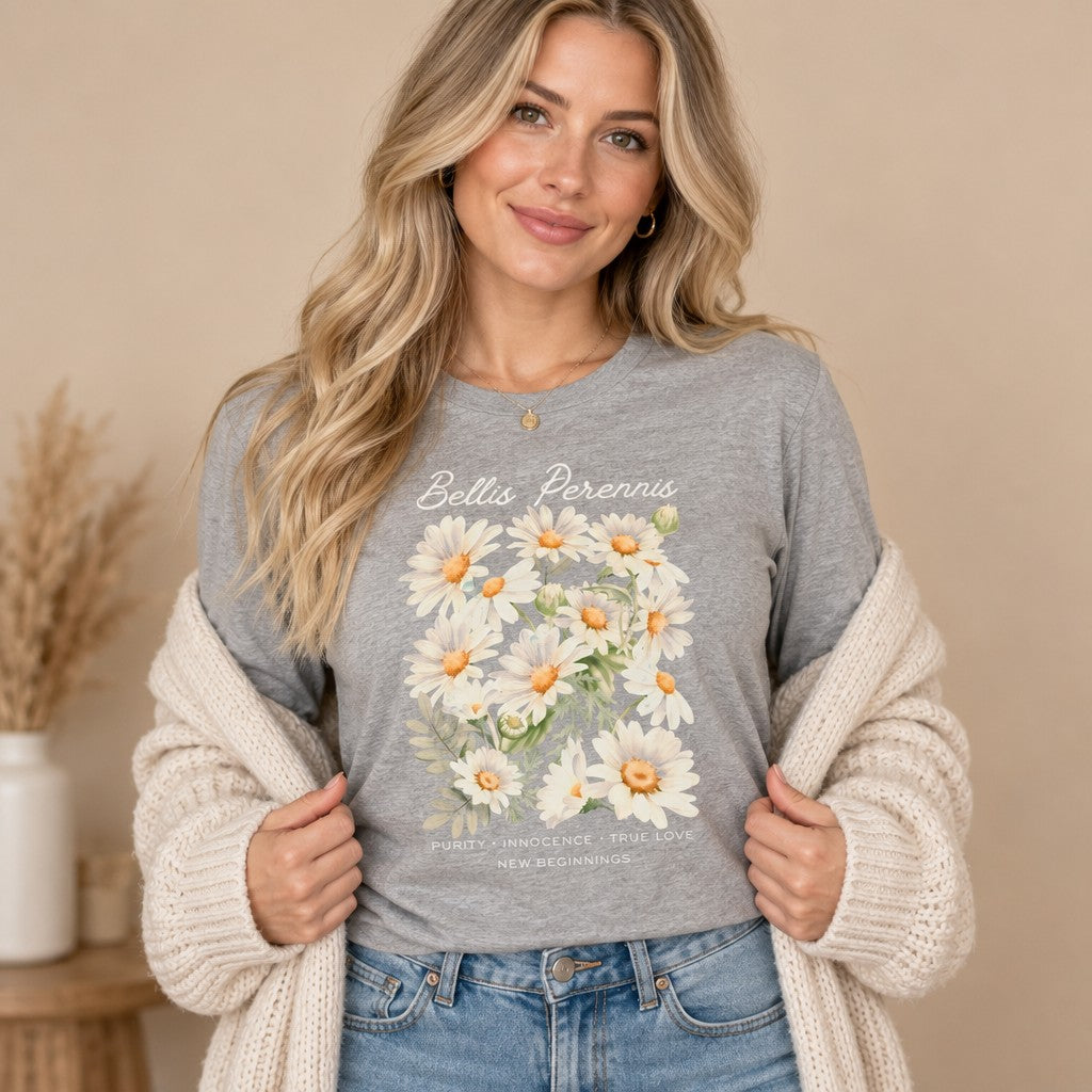Woman wearing an athletic heather Bella Canvas 3501 long sleeve shirt featuring a cottagecore watercolor design of white Bellis perennis daisies, elegant script and virtue text, styled for brides, flower lovers, and those embracing new beginnings, by Crossroads Dandelion