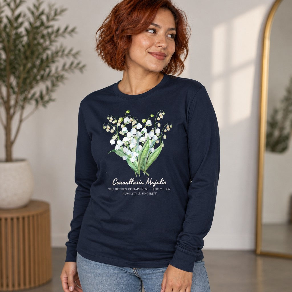 Woman in navy Bella Canvas 3501 long sleeve shirt featuring a watercolor Lily of the Valley botanical bouquet, vintage cottagecore floral design, indoor setting, perfect for floral art lovers and cottage garden enthusiasts, by Crossroads Dandelion