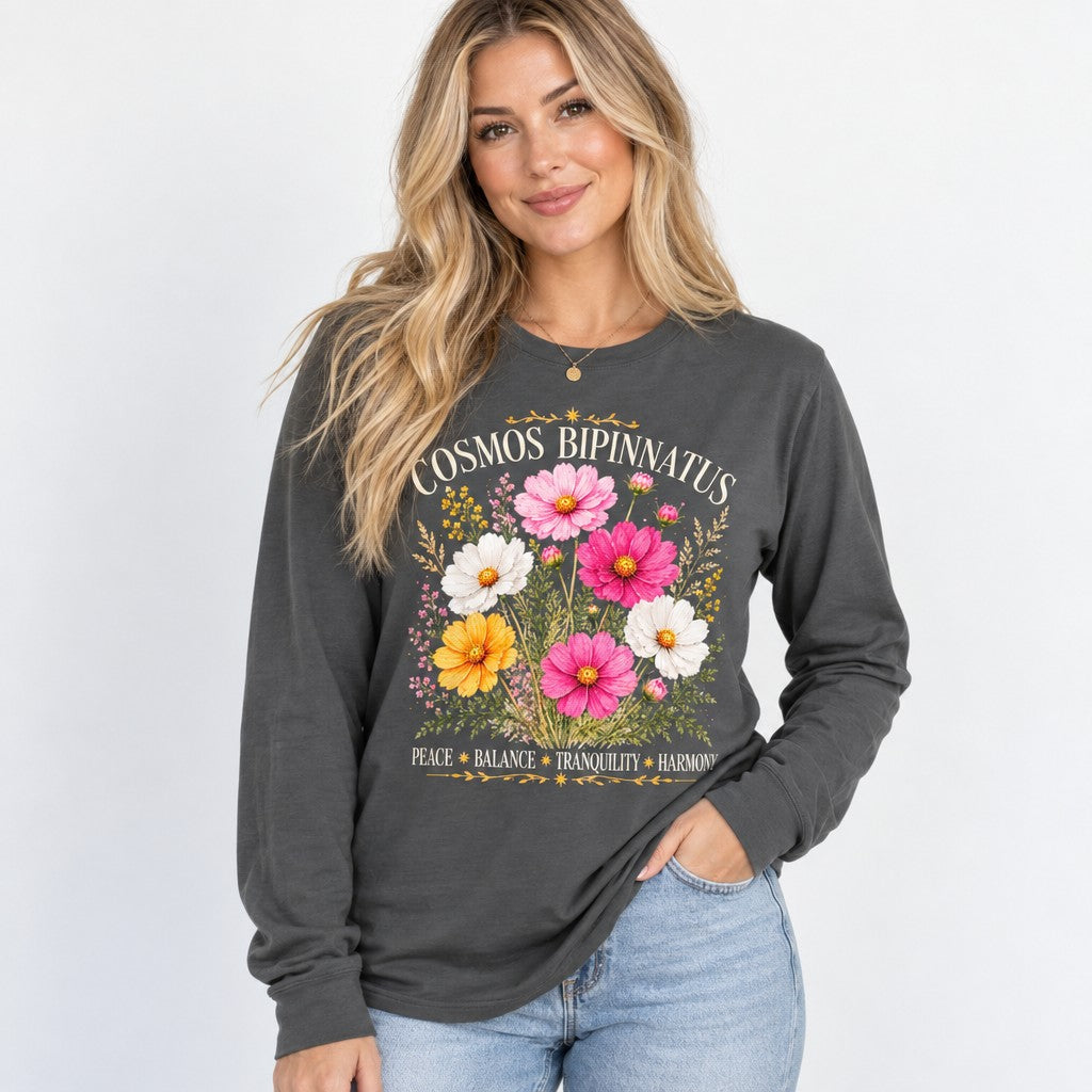 Woman wearing an asphalt Bella Canvas 3501 long sleeve featuring a vintage cottagecore watercolor bouquet of cosmos bipinnatus flowers in pink, white, and yellow with celestial gold accents, radiating peace, balance, tranquility, and harmony, perfect for October birthdays and floral lovers, by Crossroads Dandelion