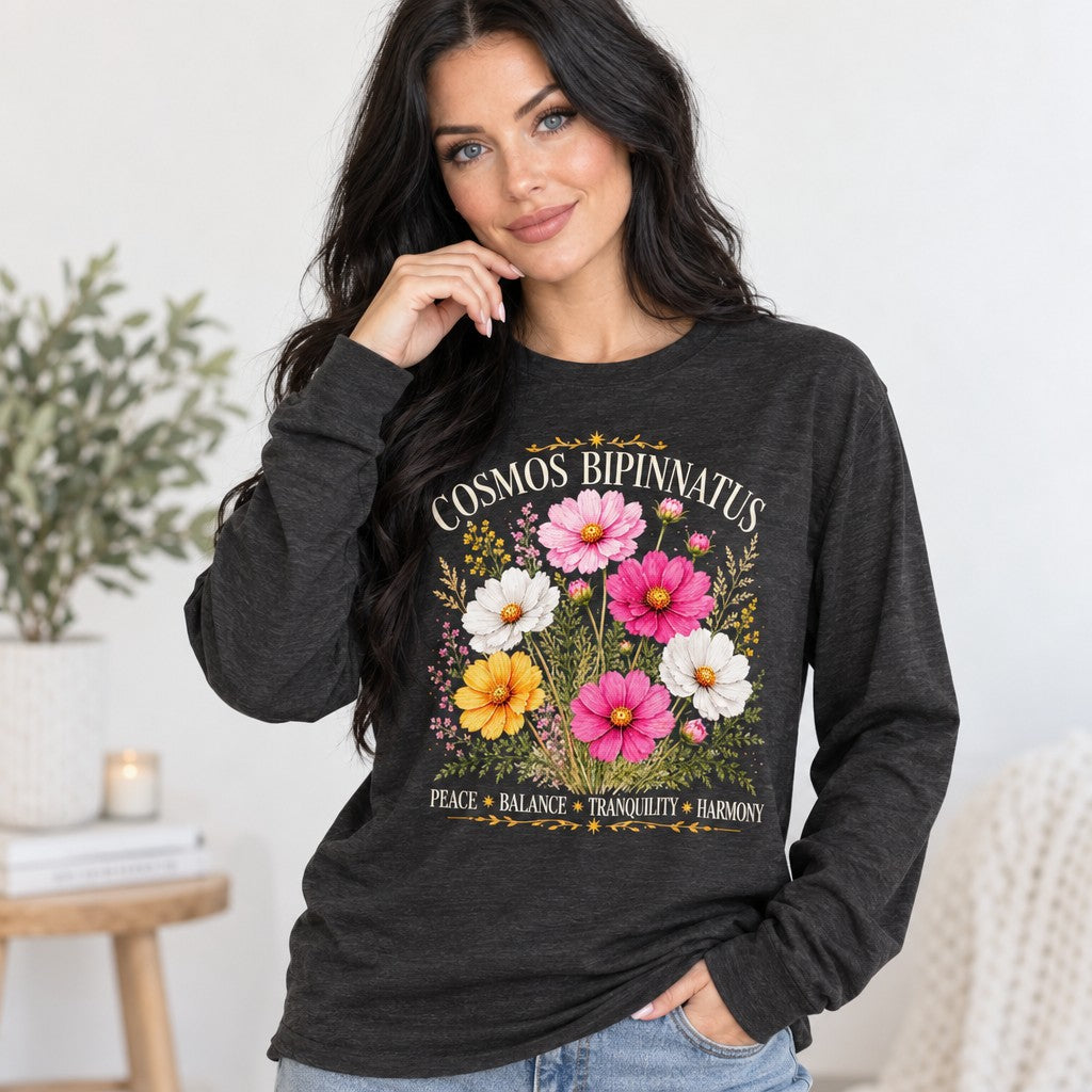 Woman in dark grey heather Bella Canvas 3501 long sleeve shirt featuring a vintage-inspired watercolor Cosmos bipinnatus floral bouquet with celestial gold accents, cottagecore style, indoor setting, perfect for botanical lovers and October birthdays, by Crossroads Dandelion
