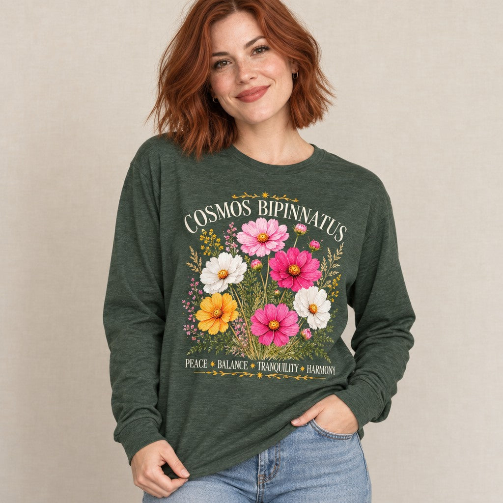 Woman wearing a heather forest Bella Canvas 3501 long sleeve featuring a vintage watercolor bouquet of Cosmos bipinnatus flowers with gold celestial accents, cottagecore botanical design focused on peace, balance, tranquility, and harmony, perfect for October birthday gifts, by Crossroads Dandelion