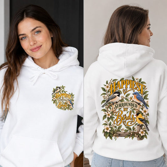 Woman wearing a white hoodie with cottagecore floral and illustrated bird design reading 'Happiest Surrounded by Birds,' cozy indoor casual outfit, perfect for bird lovers and nature enthusiasts, by Crossroads Dandelion