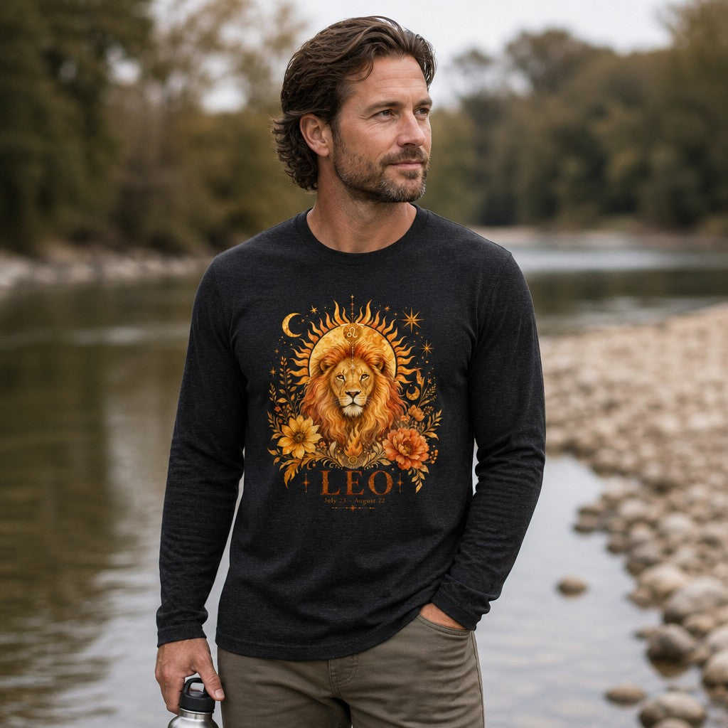 Man in dark grey heather Bella Canvas 3501 long sleeve shirt featuring a hand-painted cottagecore Leo zodiac lion surrounded by golden sunbeams, crescent moons, stars, and lush florals, standing by a riverside, perfect for astrology and botanical art lovers, by Crossroads Dandelion
