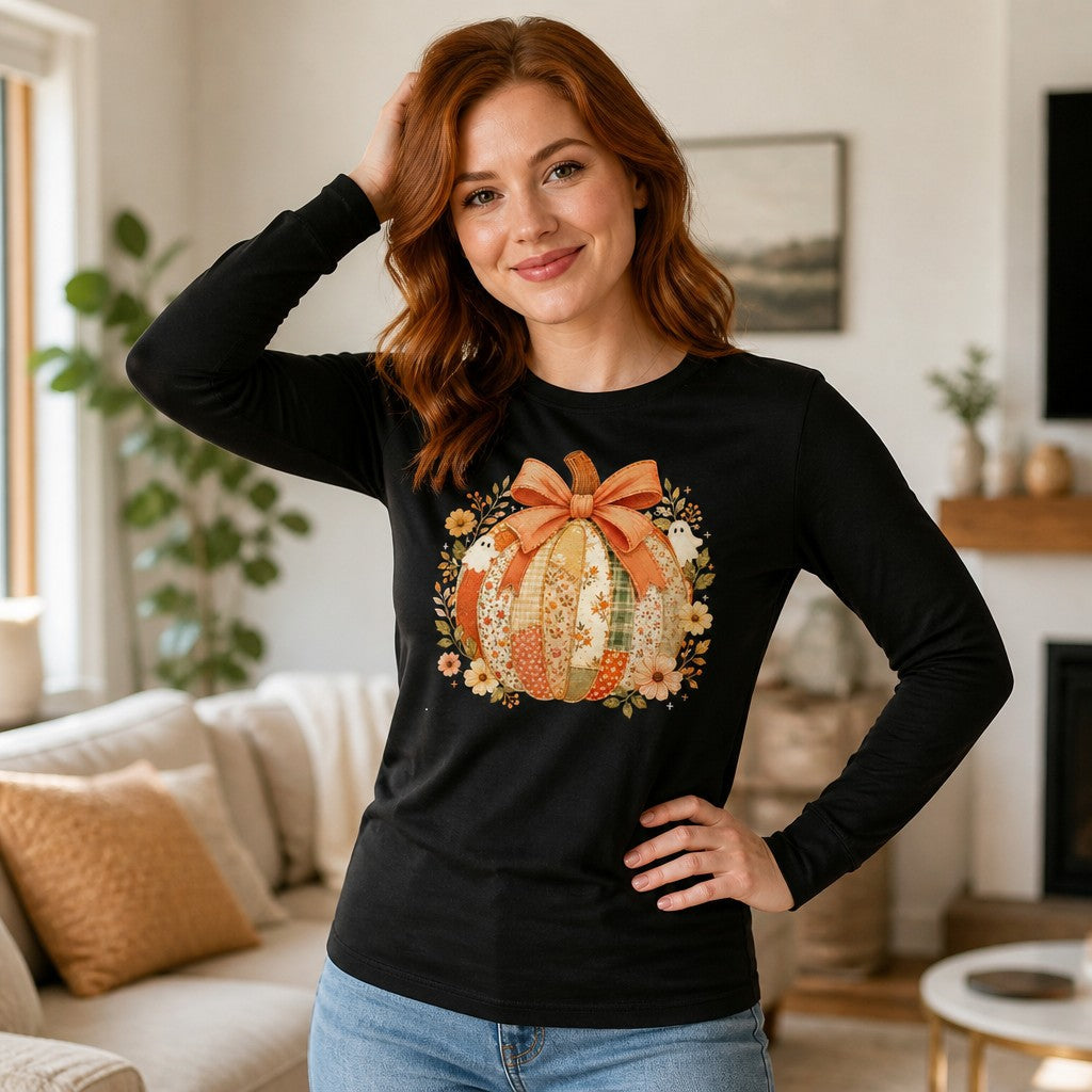 Woman in a black long sleeve Bella Canvas 3501 shirt featuring a whimsical cottagecore pumpkin patchwork floral design with vintage-style ghosts and a faded coral bow, standing in a cozy living room, autumn-inspired apparel for women, by Crossroads Dandelion