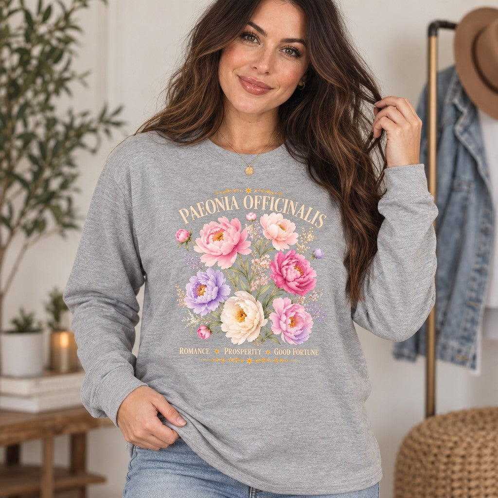 Woman wearing athletic heather Bella Canvas 3501 long sleeve with cottagecore peony and wildflower watercolor botanical design, vintage script, soft romantic floral for botanical lovers, cozy home setting, by Crossroads Dandelion