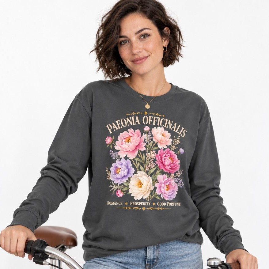 Woman wearing an asphalt Bella Canvas 3501 long sleeve shirt featuring a romantic watercolor peony and wildflower botanical script design, cottagecore vintage garden aesthetic, casual urban bike scene, for botanical and cottagecore enthusiasts, by Crossroads Dandelion
