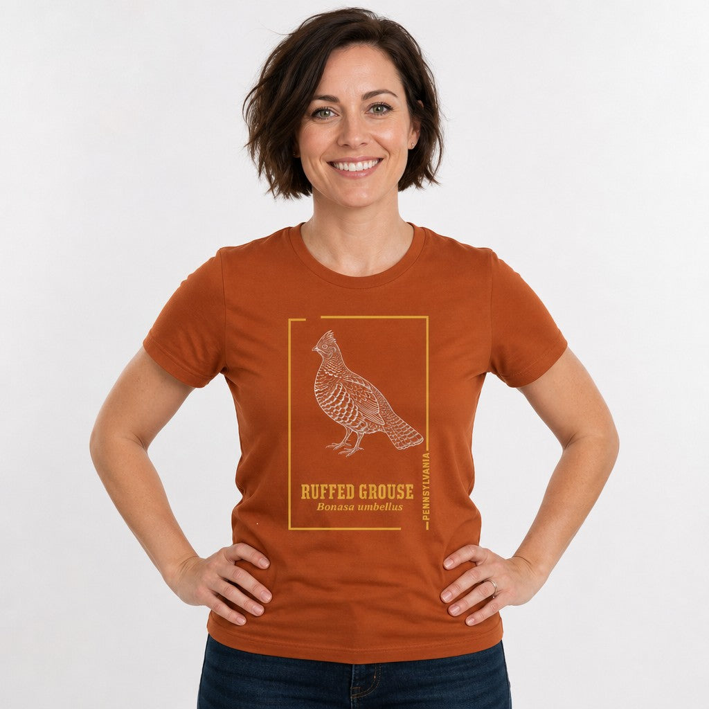 Woman wearing an autumn orange Bella Canvas 3001 t-shirt featuring a vintage, hand-drawn ruffed grouse illustration with golden accents, cottagecore and wildlife design, perfect for nature lovers, by Crossroads Dandelion