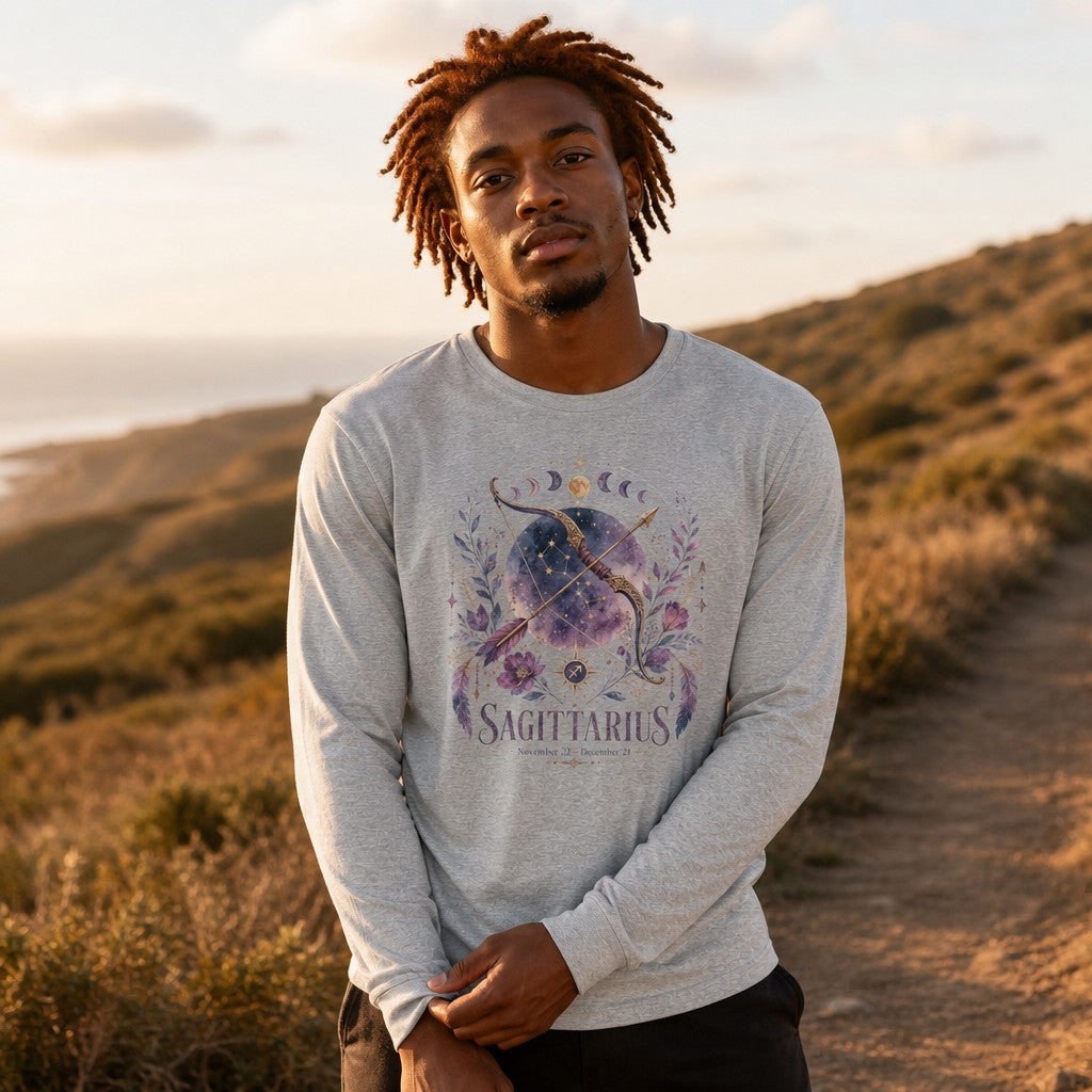Man in athletic heather long sleeve Bella Canvas 3501 featuring a watercolor Sagittarius cosmic bow and arrow entwined with purple florals, crescent moons, and stardust, mystical cottagecore zodiac design, outdoors on a hilly trail, ideal for astrology and nature lovers, by Crossroads Dandelion