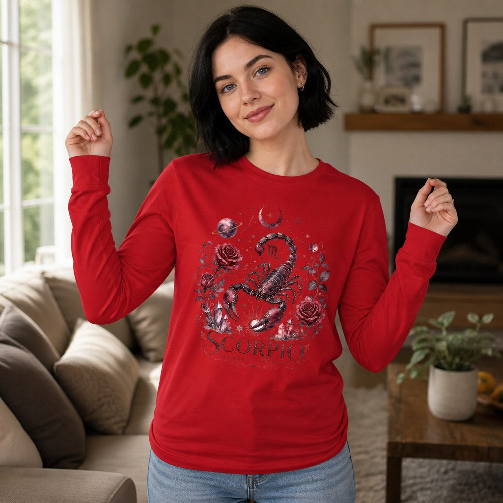 Woman wearing a red long sleeve Bella Canvas 3501 featuring a hand-painted Scorpio scorpion surrounded by deep red roses, amethyst crystals, crescent moons, and celestial elements in a vintage cottagecore botanical style, cozy living room setting, astrology lovers gift, by Crossroads Dandelion