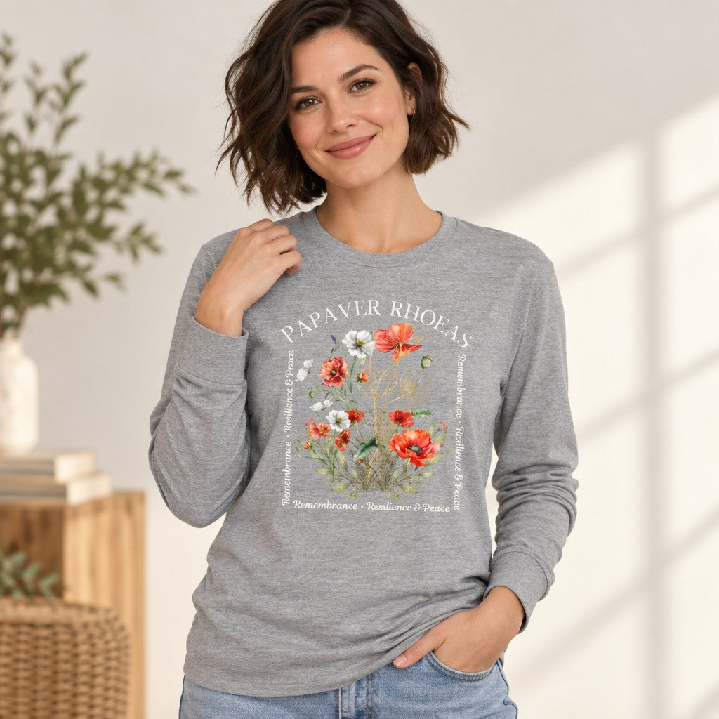 Woman in athletic heather Bella Canvas 3501 long sleeve shirt featuring a lush watercolor red, white, and blush poppy floral design with poetic text, golden botanical line art accents, and soft cottagecore aesthetic, perfect for artful nature-loving women, cozy indoor scene, by Crossroads Dandelion