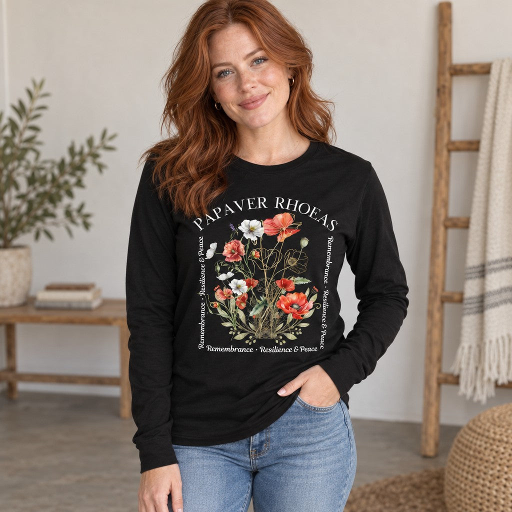 Woman in black Bella Canvas 3501 long sleeve featuring a watercolor poppy and golden botanical line art design with poetic text, cozy home setting, cottagecore style for nature-loving women, by Crossroads Dandelion