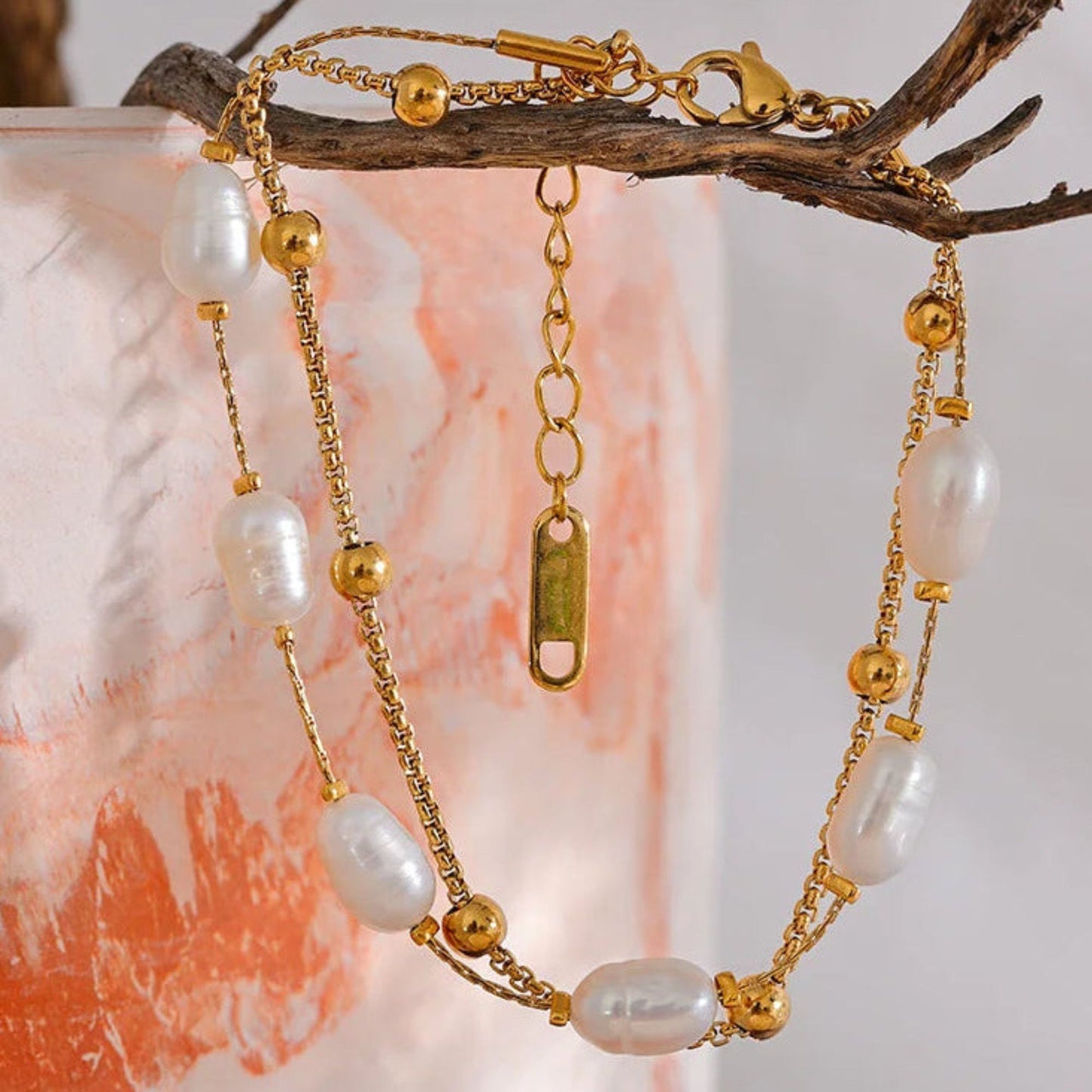 Double layer natural freshwater pearl bracelet on gold stainless steel box chain, hanging  on a decorative branch lifestyle shot by Crossroads Dandelion