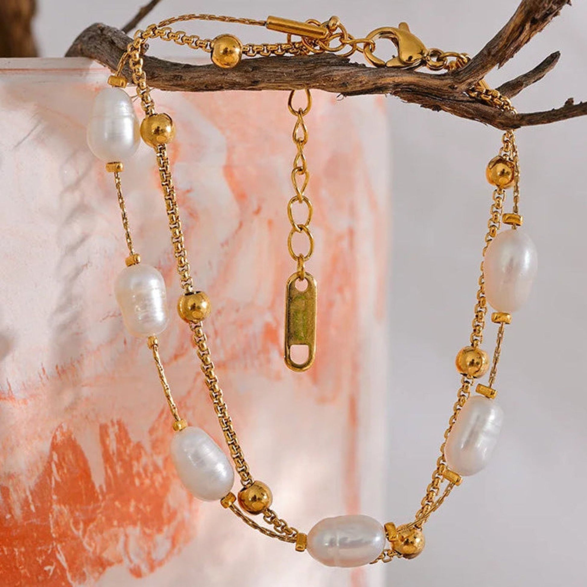 Double layer natural freshwater pearl bracelet on gold stainless steel box chain, hanging  on a decorative branch lifestyle shot by Crossroads Dandelion
