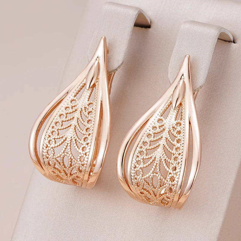 Filigree leaf teardrop earrings hanging from a cream satin jewelry display