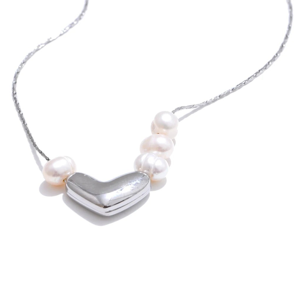 Silver puffy heart necklace with freshwater pearls on a fine chain, front view on white