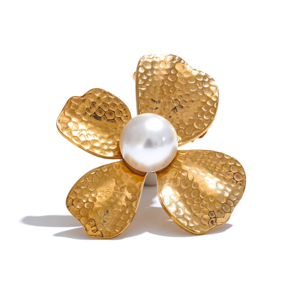 Gold flower-shaped brooch with a pearl center on a white background