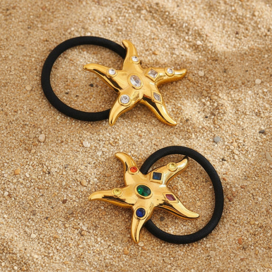Gold star-shaped hair ties with cubic zirconia gemstones on a sandy background