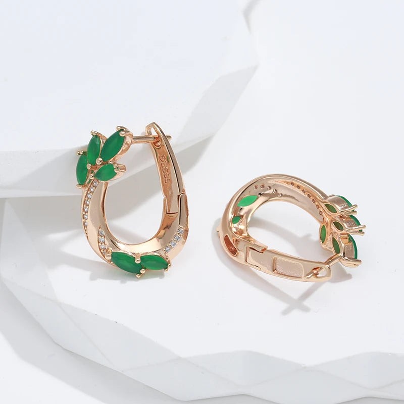 Green leaf hoop earrings with one English-lock clasp open on white stone
