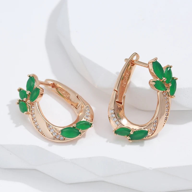 Green leaf hoop earrings in rose gold resting on a white display