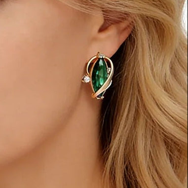 Close-up of a woman wearing a green leaf earring in a rose-gold ribbon frame