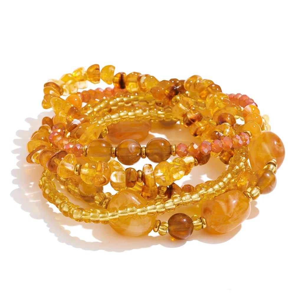 Stack of honey and golden layered beaded bracelets on white
