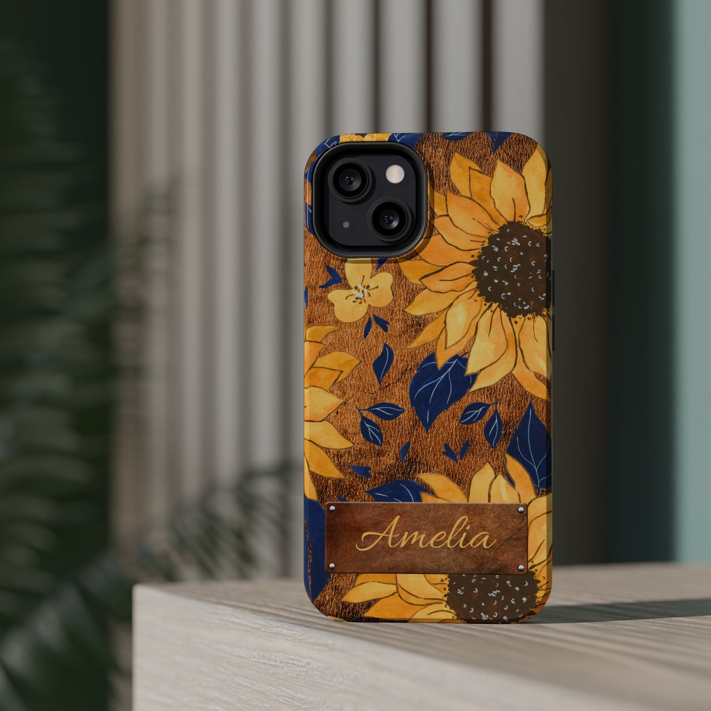 Custom name personalized sunflower western tough phone case for iPhone 13, featuring bold yellow sunflowers, navy blue leaves, rustic brown faux leather texture background, and a riveted metal name plate — perfect boho cowgirl gift, by Crossroads Dandelion