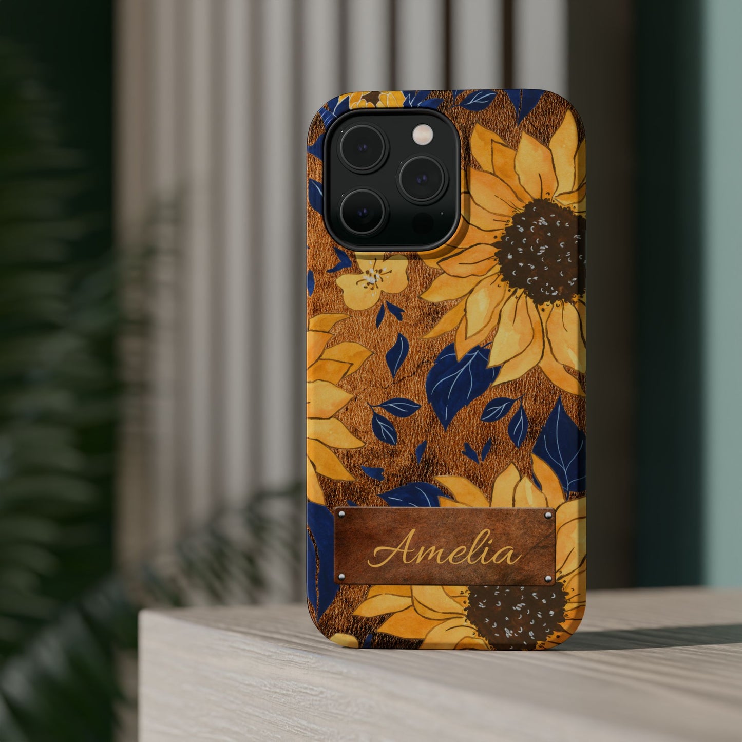 Custom name personalized sunflower western tough phone case for iPhone 14 Pro Max, featuring bold yellow sunflowers, navy blue leaves, rustic brown faux leather texture background, and a riveted metal name plate — perfect boho cowgirl gift, by Crossroads Dandelion