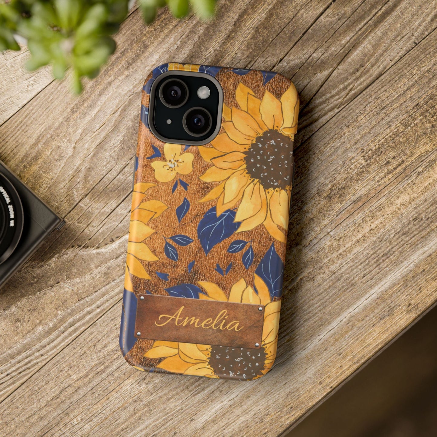Custom name personalized sunflower western tough phone case for iPhone 15, featuring bold yellow sunflowers, navy blue leaves, rustic brown faux leather texture background, and a riveted metal name plate — perfect boho cowgirl gift, by Crossroads Dandelion