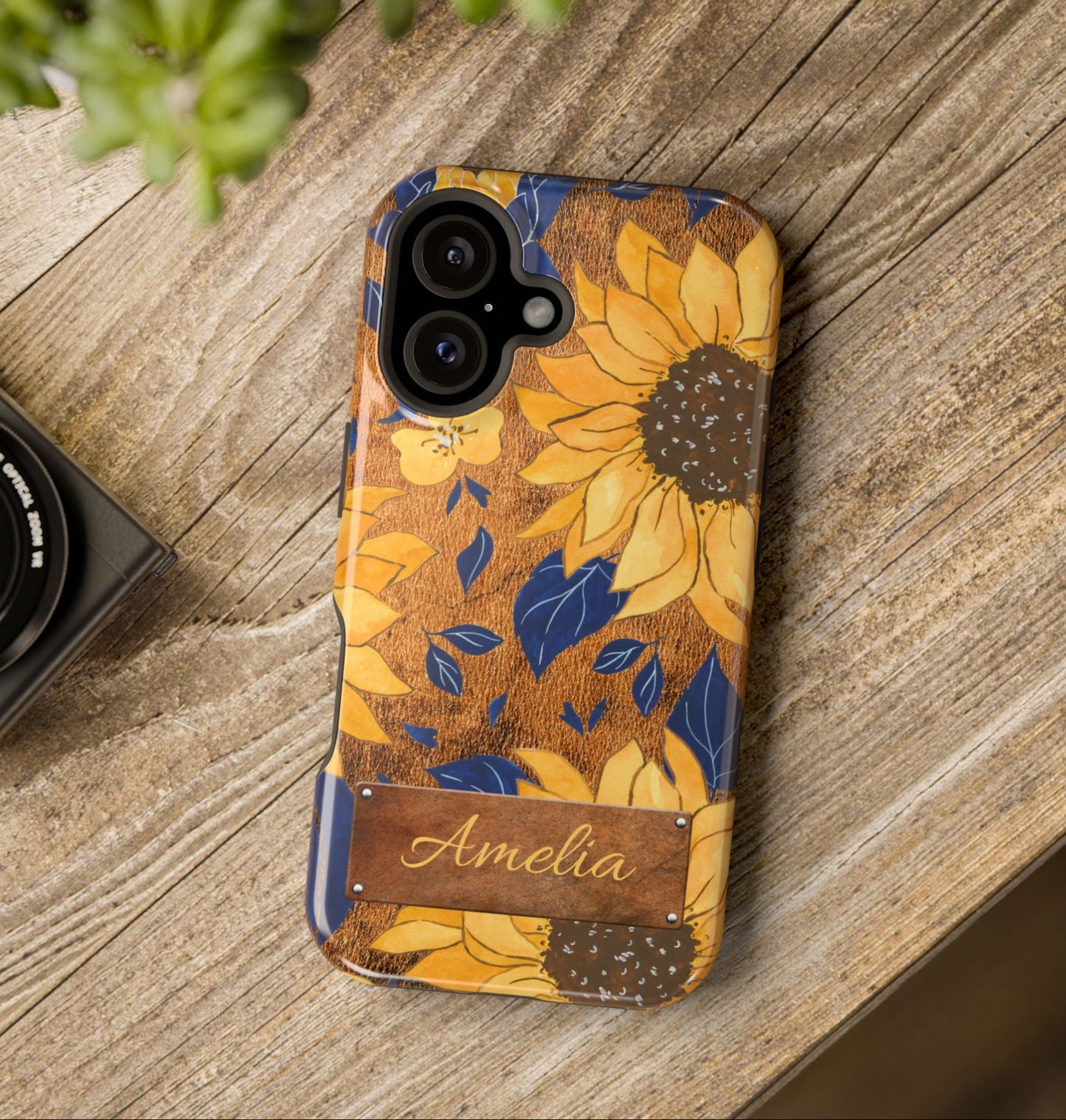 Custom name personalized sunflower western tough phone case for iPhone 16, featuring bold yellow sunflowers, navy blue leaves, rustic brown faux leather texture background, and a riveted metal name plate — perfect boho cowgirl gift, by Crossroads Dandelion