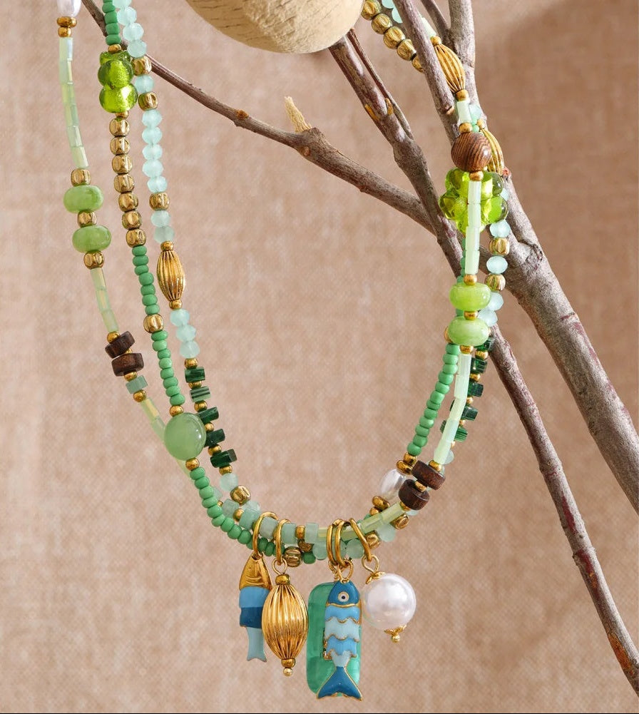 Beaded necklace with colorful charms on a branch against a beige background